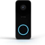 WYZE Video Doorbell with a compact white and black design mounted beside a front door, showing a clear HD video of a visitor. The smart doorbell features motion detection and two-way audio, highlighting its integration with the WYZE app for remote access and real-time notifications.