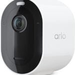 Arlo Pro Smart Camera with a sleek, compact white and black design, mounted outside a modern home, capturing HD video footage. The camera is equipped with night vision and motion detection, emphasizing its wireless setup and compatibility with Alexa and Google Assistant for enhanced smart home security.