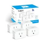 TP-Link Tapo Smart Plug with a compact white design, plugged into a wall socket in a modern living room, controlling a lamp. The smart plug emphasizes Wi-Fi connectivity and compatibility with Alexa and Google Assistant for voice control and smart scheduling.