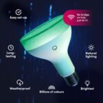LIFX Smart Light bulb with a sleek white design, installed in a modern bedroom lamp, emitting a vibrant purple hue. The smart light is demonstrating its ability to change colors and brightness, emphasizing its compatibility with Alexa, Google Assistant, and Apple HomeKit for voice-activated control.